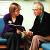 Photograph of CancerBACUP nurse and man looking at a booklet