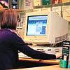 Photograph of a nurse using the CancerBACUP website on a computer in a local centre